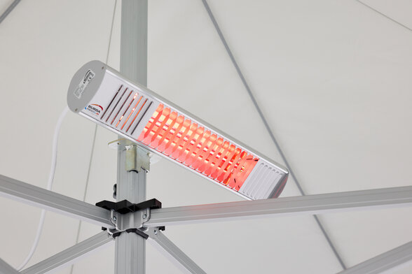 The heater is mounted on the central pole of the folding gazebo. The radiant heater is on.