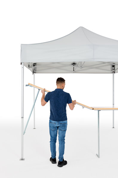 The man assembles the wooden counter on the folding gazebo.